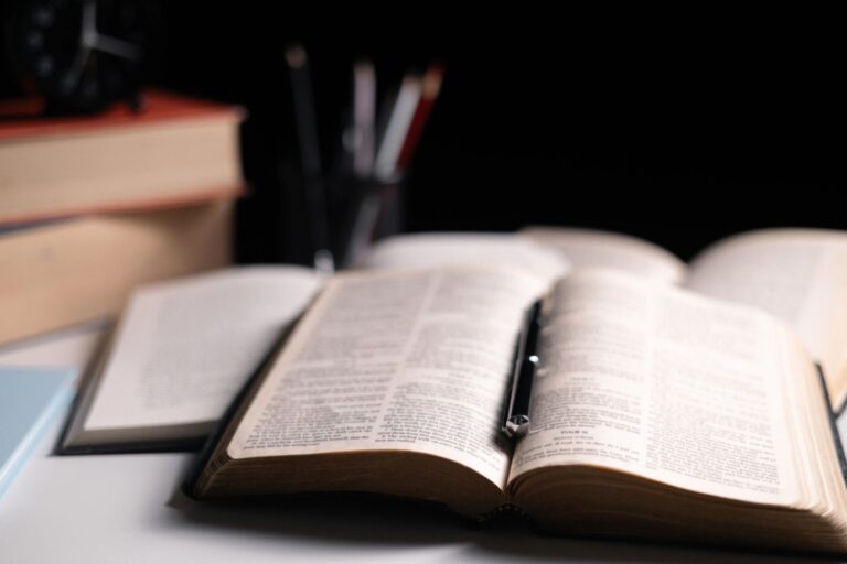 Old library, an open Bible lay on the table, its holy pages of scripture illuminated in the dark room. bible, holy, dark, old, open, library, pages, scripture, table, book, page.